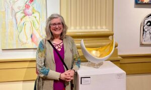Michaele Rose Watson in art gallery standing next to her sculpture "Tracy's Belly" on a pedestal