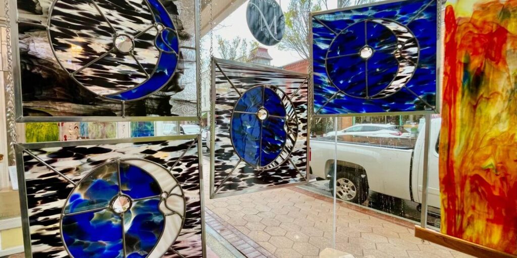 Blue and white moon and stars stained glass panels hanging in shop window