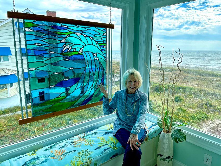 Linda sitting in on bench with blue wave stained glass panel installed