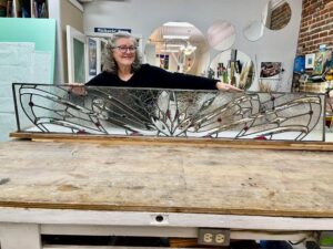 Woman smiling holding a stained glass transom