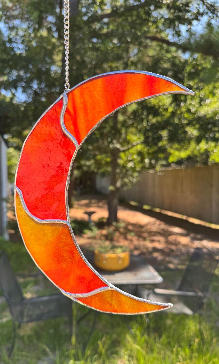 Orange stained glass crescent moon suncatcher hanging on metal chain
